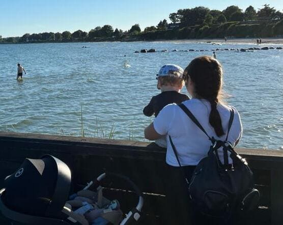Mama con bebé delante de un lago atendida por doula barcelona